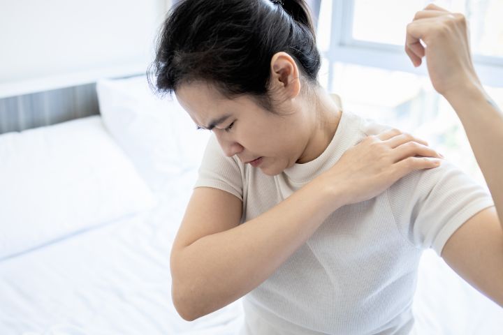 痛い肩を回している女性